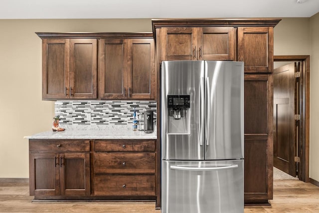 3830 Augusta Ct, Plover, WI 54467 - kitchen featuring stainless steel refrigerator with ice dispenser, dark brown cabinetry, backsplash, light wood-style floors, and light stone counters