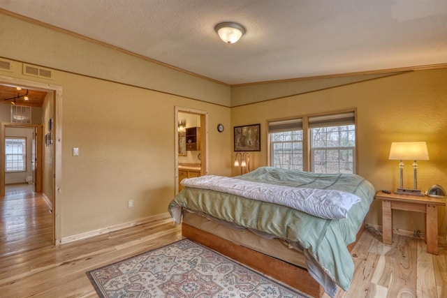 7760 N Thunder Point Rd, Hayward, WI 54843 - bedroom with light wood-type flooring, a textured wall, ornamental molding, a textured ceiling, and connected bathroom