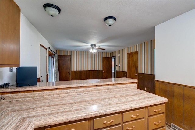 1702 Rae Ln, Madison, WI 53711 - kitchen featuring light countertops, a wainscoted wall, a ceiling fan, wallpapered walls, and brown cabinets