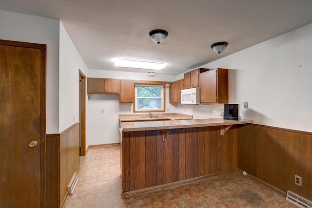 1702 Rae Ln, Madison, WI 53711 - kitchen with white microwave, a peninsula, brown cabinets, light floors, and wainscoting