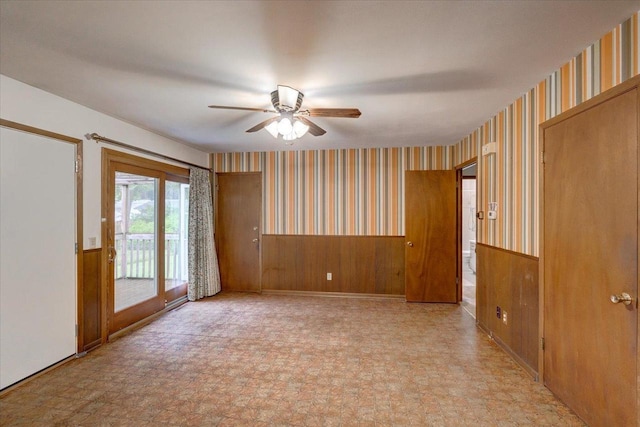 1702 Rae Ln, Madison, WI 53711 - unfurnished room featuring wallpapered walls, a ceiling fan, a wainscoted wall, wood walls, and light floors