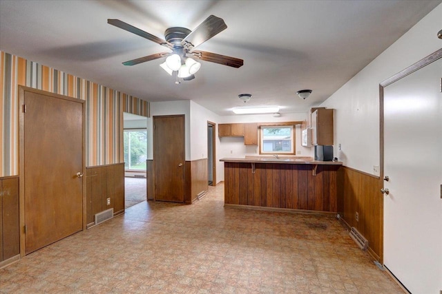 1702 Rae Ln, Madison, WI 53711 - kitchen with wainscoting, a peninsula, brown cabinets, wooden walls, and light countertops