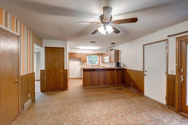 1702 Rae Ln, Madison, WI 53711 - kitchen with a peninsula, wainscoting, a ceiling fan, white microwave, and brown cabinetry