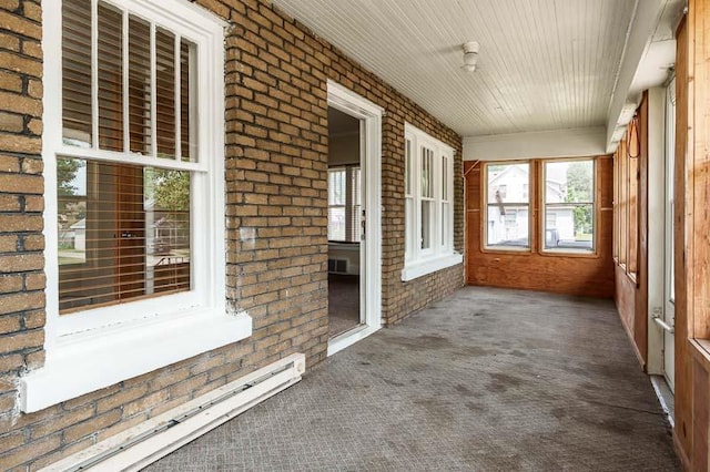 619 Middle St, Beloit, WI 53511 - unfurnished sunroom featuring baseboard heating, brick wall, carpet floors, and wood ceiling