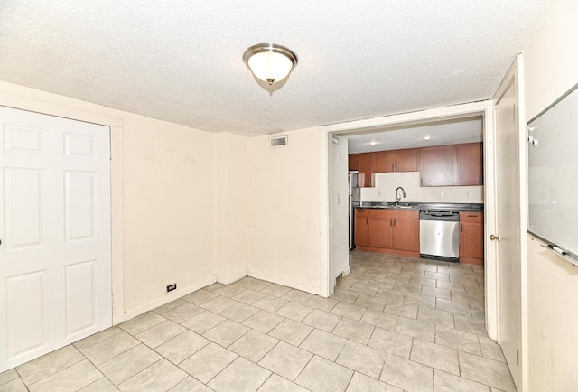 1721 Spring Pl, Racine, WI 53404 - kitchen with stainless steel appliances, dark countertops, a textured ceiling, brown cabinetry, and light tile patterned floors