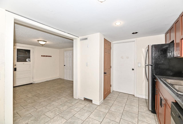 1721 Spring Pl, Racine, WI 53404 - kitchen with dishwasher, brown cabinetry, dark countertops, light tile patterned flooring, and freestanding refrigerator