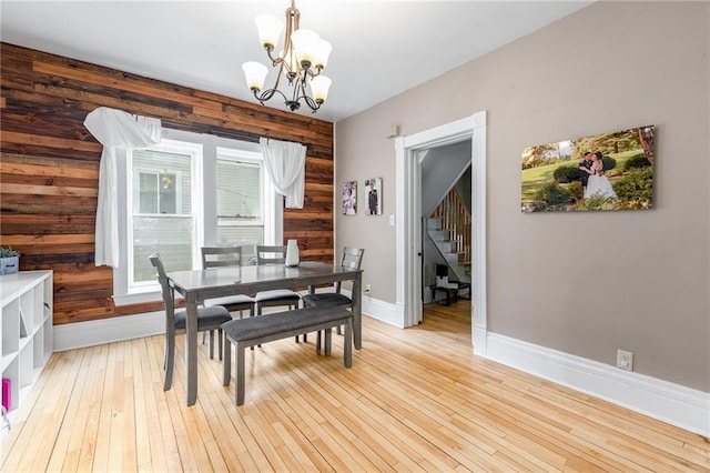 508 Evergreen St, Colfax, WI 54730 - dining space featuring a chandelier, stairway, wooden walls, and light wood-type flooring