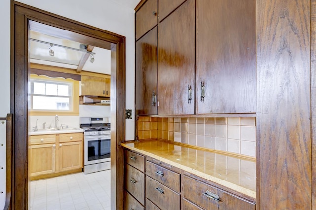 518 Maple Ave, Madison, WI 53704 - kitchen with stainless steel gas range oven, decorative backsplash, under cabinet range hood, and track lighting