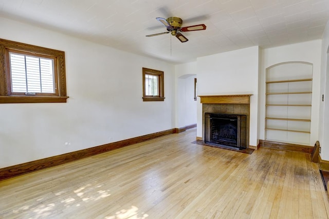 518 Maple Ave, Madison, WI 53704 - unfurnished living room with built in features, hardwood / wood-style floors, a tiled fireplace, ceiling fan, and arched walkways