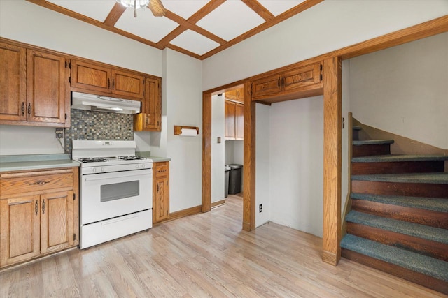 2140 N 64th St, Wauwatosa, WI 53213 - kitchen featuring white range with gas stovetop, under cabinet range hood, decorative backsplash, a ceiling fan, and light wood-type flooring