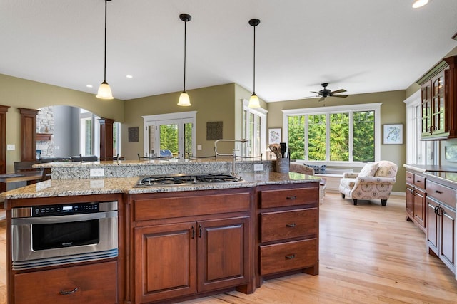 14595 Louis Corners Rd, Kiel, WI 53042 - kitchen featuring open floor plan, ornate columns, stainless steel gas stovetop, a ceiling fan, and light wood-style floors