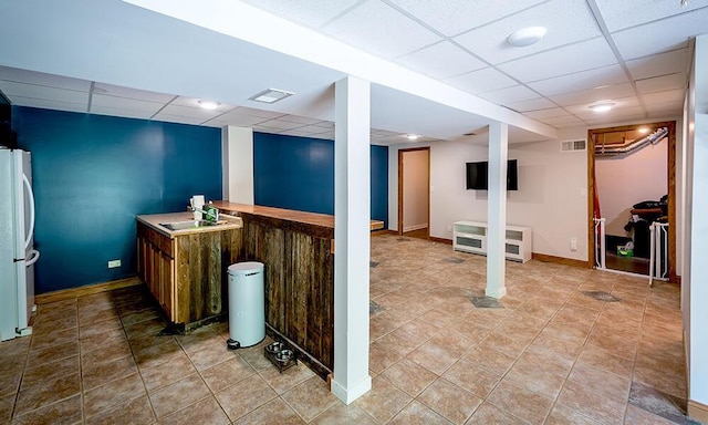 11812 Fox River Rd, Twin Lakes, WI 53181 - finished basement with a paneled ceiling, freestanding refrigerator, heating unit, bar area, and light tile patterned flooring