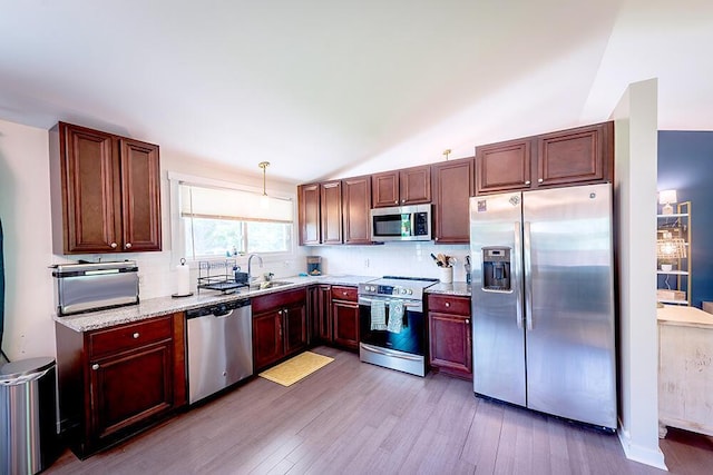11812 Fox River Rd, Twin Lakes, WI 53181 - kitchen with appliances with stainless steel finishes, light wood-style floors, backsplash, vaulted ceiling, and light stone countertops