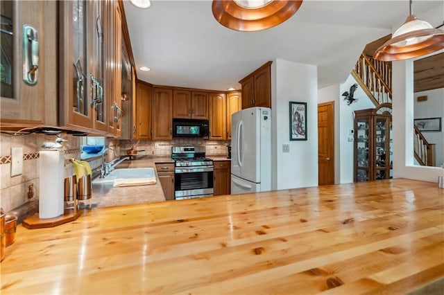 9926 W Birch Circle Dr, Ladysmith, WI 54848 - kitchen with stainless steel gas range oven, black microwave, freestanding refrigerator, wooden counters, and glass insert cabinets