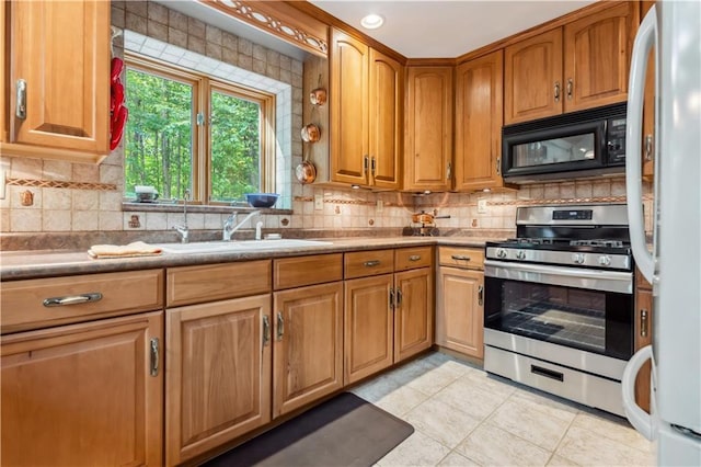 9926 W Birch Circle Dr, Ladysmith, WI 54848 - kitchen with black microwave, stainless steel range with gas cooktop, freestanding refrigerator, light tile patterned floors, and backsplash