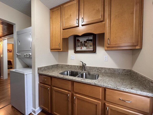 8 Balsam Trl, Wisconsin Dells, WI 53965 - kitchen featuring stacked washer / dryer, dark wood finished floors, brown cabinets, stone countertops, and a textured ceiling