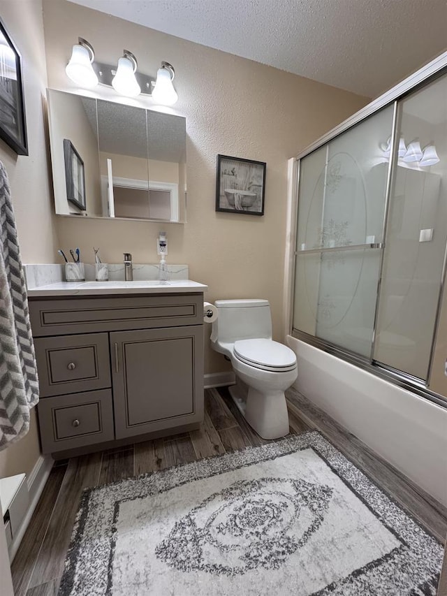 8 Balsam Trl, Wisconsin Dells, WI 53965 - bathroom featuring wood finished floors, vanity, shower / bath combination with glass door, and a textured ceiling