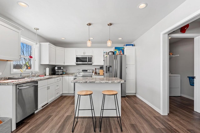 400 Tristan Dr, Shawano, WI 54166 - kitchen with appliances with stainless steel finishes, washer / clothes dryer, dark wood-style flooring, a center island, and white cabinetry