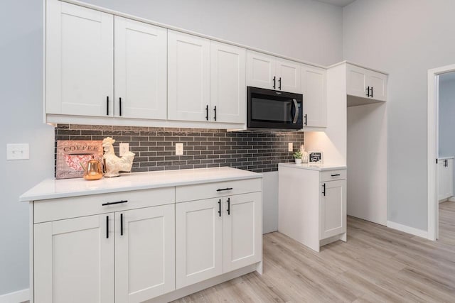 922 Vogt Ln, Chilton, WI 53014 - kitchen featuring black microwave, white cabinetry, backsplash, light wood-type flooring, and light countertops