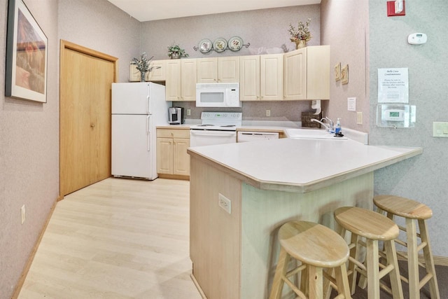 8530 Greenway Blvd Unit 104, Middleton, WI 53562 - kitchen featuring white appliances, a kitchen bar, light wood finished floors, a peninsula, and light countertops