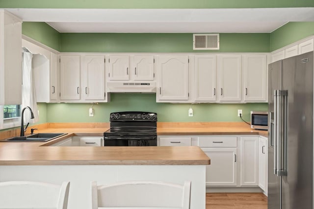 W330S7517 Split Rail Dr, Mukwonago, WI 53149 - kitchen featuring stainless steel appliances, under cabinet range hood, a peninsula, light countertops, and white cabinetry
