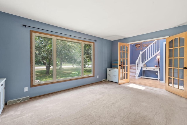 W330S7517 Split Rail Dr, Mukwonago, WI 53149 - unfurnished room featuring healthy amount of natural light, french doors, carpet flooring, and stairs