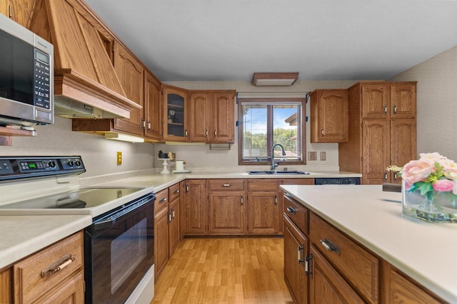 6352 Black Wolf Point Ln, Oshkosh, WI 54902 - kitchen with range with electric cooktop, stainless steel microwave, brown cabinets, light wood finished floors, and custom exhaust hood