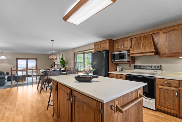 6352 Black Wolf Point Ln, Oshkosh, WI 54902 - kitchen with range with electric stovetop, freestanding refrigerator, stainless steel microwave, brown cabinetry, and light wood-style floors