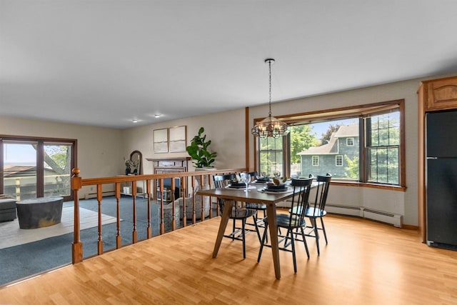 6352 Black Wolf Point Ln, Oshkosh, WI 54902 - dining area featuring light wood-type flooring, a baseboard radiator, and a chandelier