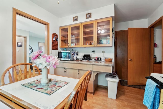 38 Bowen St, Oshkosh, WI 54901 - kitchen featuring stainless steel microwave, light wood finished floors, stove, glass insert cabinets, and tile counters