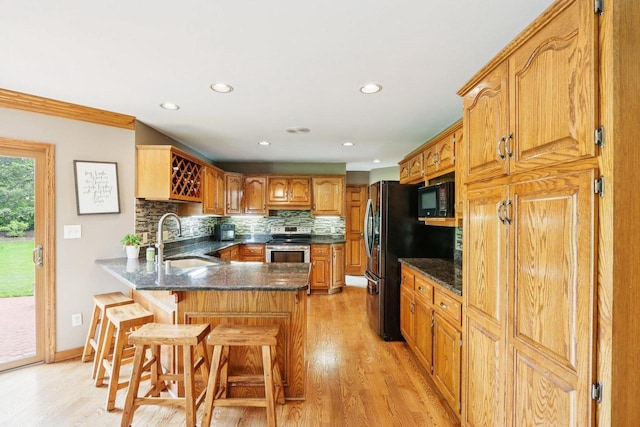 W151N10146 W Windsong Cir, Germantown, WI 53022 - kitchen featuring stainless steel range with electric stovetop, black microwave, a peninsula, light wood-style floors, and decorative backsplash