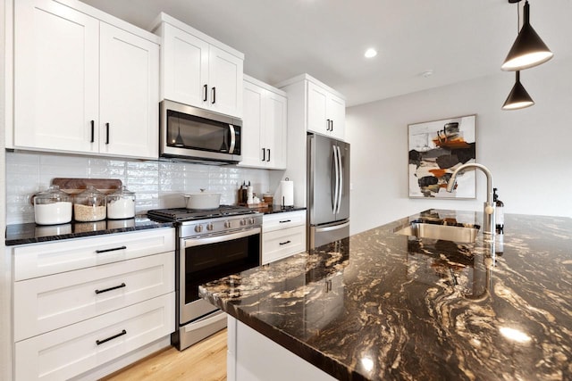 1887 Woodland Way, Slinger, WI 53086 - kitchen featuring appliances with stainless steel finishes, decorative backsplash, white cabinetry, pendant lighting, and dark stone countertops