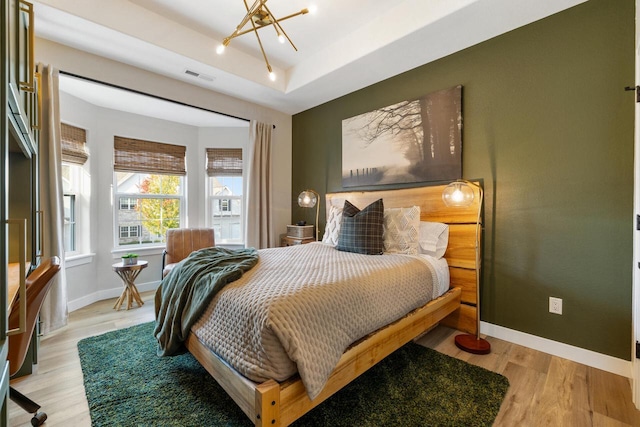 1887 Woodland Way, Slinger, WI 53086 - bedroom with light wood-style floors, a raised ceiling, and a chandelier