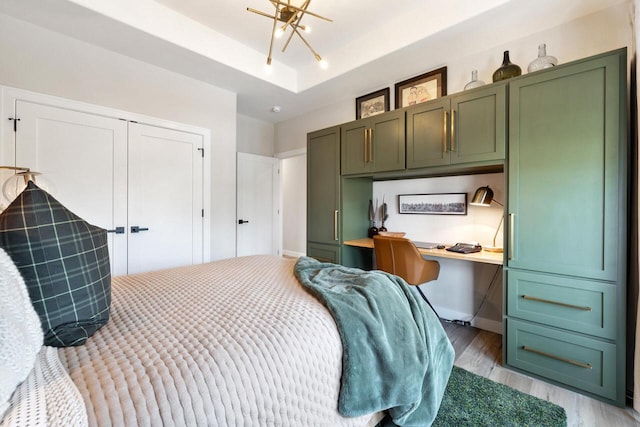1887 Woodland Way, Slinger, WI 53086 - bedroom featuring built in study area, a raised ceiling, light wood-style floors, and a closet