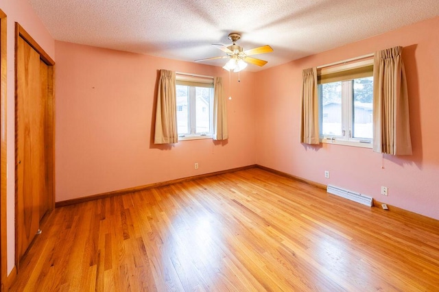 3424 Geneva Ln, La Crosse, WI 54601 - unfurnished bedroom featuring light wood-style floors, a textured ceiling, baseboard heating, a ceiling fan, and a closet