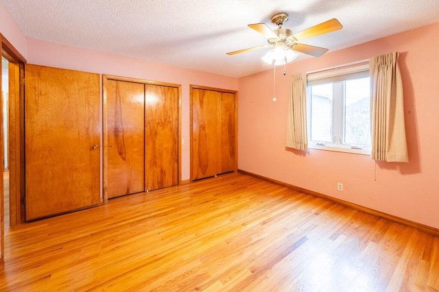 3424 Geneva Ln, La Crosse, WI 54601 - unfurnished bedroom with light wood-style flooring, two closets, a textured ceiling, and ceiling fan