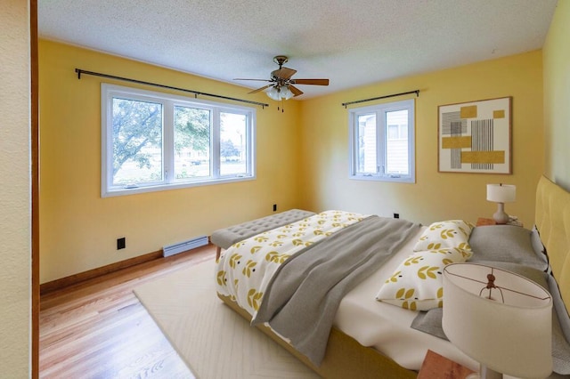 3424 Geneva Ln, La Crosse, WI 54601 - bedroom featuring baseboard heating, wood finished floors, a textured ceiling, and ceiling fan