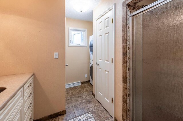 3424 Geneva Ln, La Crosse, WI 54601 - full bath featuring stacked washer and clothes dryer, vanity, tile patterned flooring, and a shower stall