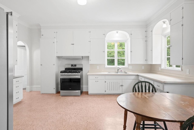 204 E Huron St, Berlin, WI 54923 - kitchen with stainless steel appliances, white cabinetry, under cabinet range hood, light countertops, and ornamental molding