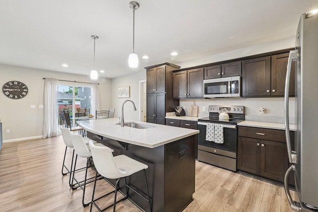 6017 Lyda Woods Ln, Madison, WI 53718 - kitchen with stainless steel appliances, dark brown cabinetry, a breakfast bar, light wood-type flooring, and recessed lighting
