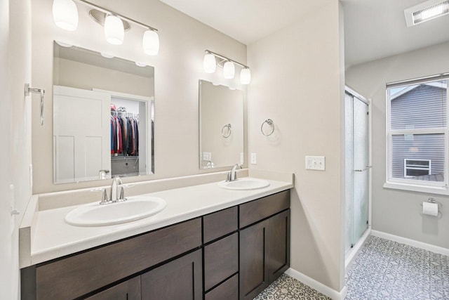6017 Lyda Woods Ln, Madison, WI 53718 - bathroom with double vanity, a shower stall, tile patterned floors, and a walk in closet