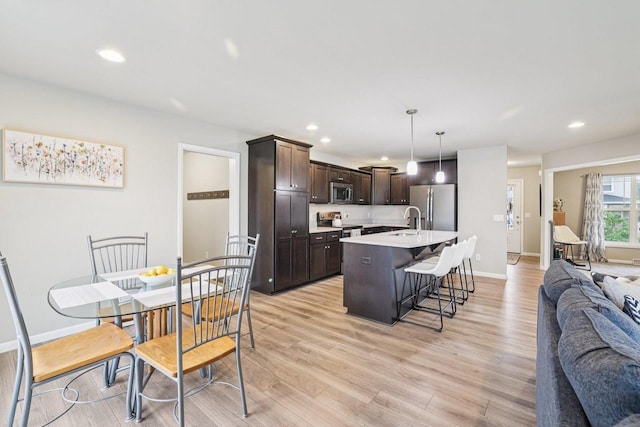 6017 Lyda Woods Ln, Madison, WI 53718 - kitchen with stainless steel appliances, open floor plan, dark brown cabinetry, a kitchen breakfast bar, and light countertops