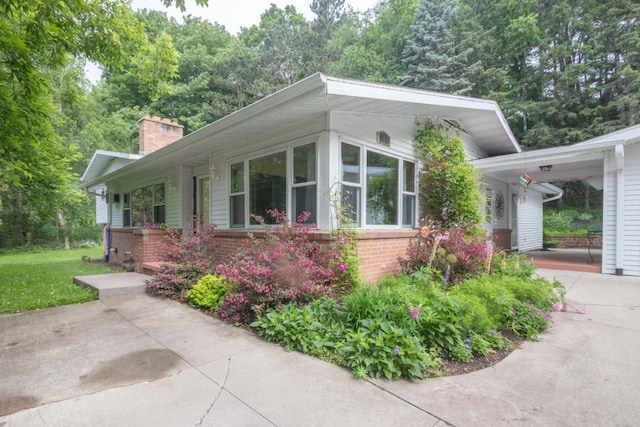 1718 N 13th St, Wausau, WI 54403 - view of front of house featuring brick siding, a chimney, and a carport