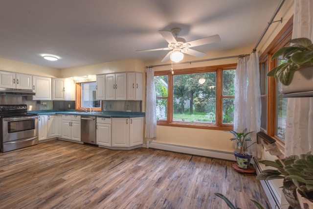 1718 N 13th St, Wausau, WI 54403 - kitchen with stainless steel appliances, baseboard heating, under cabinet range hood, and white cabinets