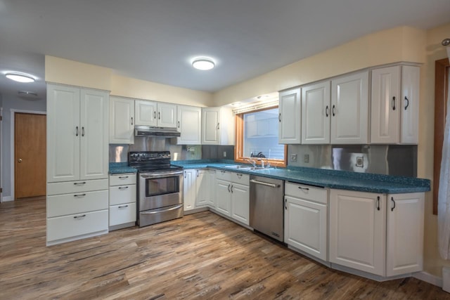 1718 N 13th St, Wausau, WI 54403 - kitchen featuring stainless steel appliances, under cabinet range hood, dark countertops, and white cabinetry