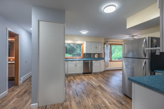 1718 N 13th St, Wausau, WI 54403 - kitchen featuring appliances with stainless steel finishes, white cabinetry, wood finished floors, dark countertops, and a baseboard heating unit