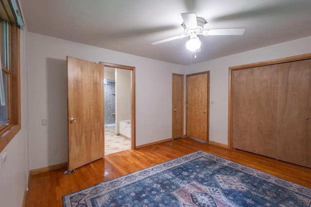 1718 N 13th St, Wausau, WI 54403 - unfurnished bedroom featuring wood finished floors, two closets, ensuite bath, and a ceiling fan