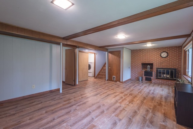 1718 N 13th St, Wausau, WI 54403 - unfurnished living room featuring stairs, light wood finished floors, washer / dryer, a brick fireplace, and beamed ceiling