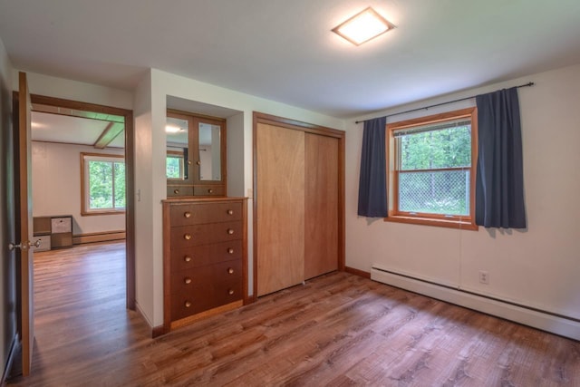 1718 N 13th St, Wausau, WI 54403 - unfurnished bedroom with a baseboard heating unit, wood finished floors, and multiple windows