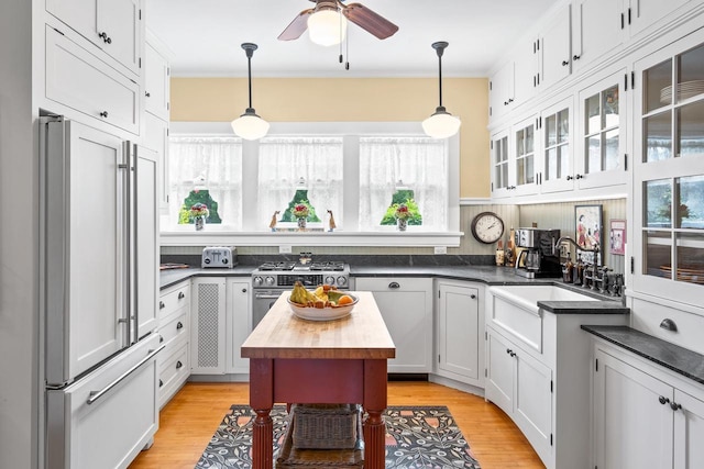 730 3rd St S, Wisconsin Rapids, WI 54494 - kitchen featuring paneled refrigerator, gas range, a ceiling fan, pendant lighting, and glass insert cabinets